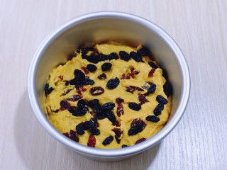 4、奶香果干南瓜发糕,将6寸活底蛋糕模具刷上一层食用油(以便脱模)取一半拌好的南瓜面糊放入模具中,抹平,撒上洗干净的黑加仑干与蔓越莓干!