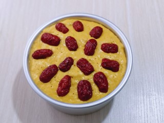 9、奶香果干南瓜发糕,40分钟后蒸烤箱鸣笛,打开盖子将模具取出,发酵的特别好,红枣去核,用剪刀剪开,(一颗枣剪二半)摆放在发酵好的南瓜面糊上!