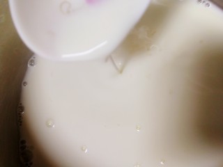 5、椰奶小方【零失败】,把牛奶玉米淀粉液一点一点加入热奶锅里，不断搅拌推动奶锅底部。