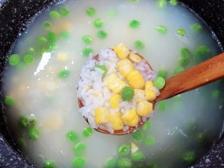 9、冬日暖心菜 扇贝田园砂锅粥,粥煮至7成熟时,加入豌豆和玉米粒,搅拌均匀,继续小火熬煮。