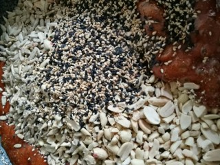 8、花生瓜籽麻糖,糖浆熬好后关火,将温热的花生碎、芝麻、葵花籽仁倒入熬好的糖浆中,快速拌匀。