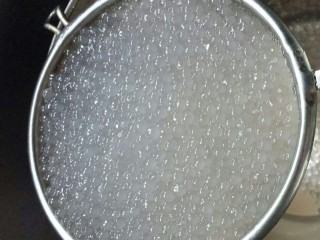 4、杨枝甘露,西米煮好后用凉开水把表面的黏夜冲洗干净。凉开水倒入锅中，加入白糖加热搅拌至融化糖水倒出放凉备用。