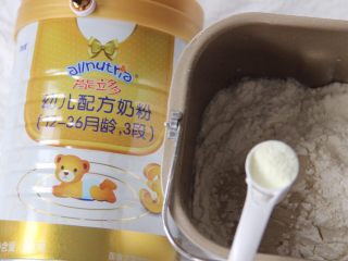 2、猪猪馒头,干酵母加入温水中化开，倒入面粉中，加入两勺奶粉，用筷子搅拌成絮状，用手揉至表面光滑的面团（有面包机的话直接将食材放入面包机里）