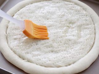 6、芝士榴莲披萨,将烤好的饼底取出来，用刷子在表面刷上一层薄薄的橄榄油。