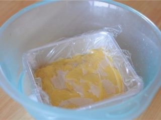 7、#不一样的泡芙#卡仕达焦糖泡芙塔,立刻倒入托盘里，抹平。趁热紧贴着卡士达酱盖上保鲜膜，放在冰水里降温