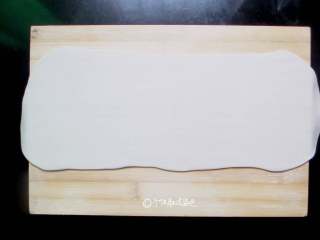 2、死面卷子,晾凉的面团放到撒了薄面的案板上，擀成厚度约为1-2毫米的长方形面片。