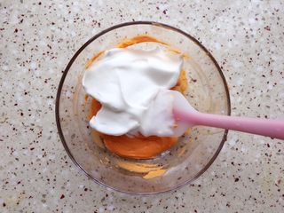 10、胡萝卜溶豆,分3/1蛋白霜到胡萝卜泥碗里,翻拌均匀;