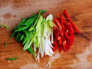 2、土豆丝红椒煎春卷,蒜苗洗净后用刀切丝，红椒用刀切丝。