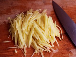 3、土豆丝红椒煎春卷,土豆去皮洗净后用刀切成丝后，用清水冲洗一下。