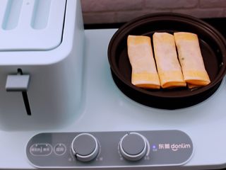 16、土豆丝红椒煎春卷,东菱早餐机的煎锅里倒入少许油，把做好的春卷放入锅中。