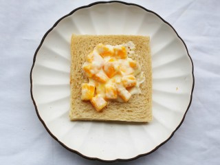 7、好吃到爆的酸奶芒果土司,取2勺芒果酸奶抹在土司上。