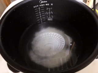 15、生滚牛肉粥,把淘好的米放进电饭煲内胆里加合适的水量；