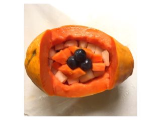 6、木瓜水果船#甜蜜美味#,把黑加仑葡萄、香梨块、木瓜块摆放在木瓜船里。