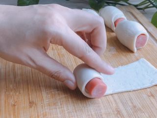 4、香肠飞饼卷,放上小香肠，从尖端的一头卷起