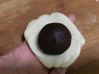 15、蛋黄豆沙酥,松弛之后,我们取一份面团,将两端向中间聚拢,再将其整理成圆形,中间放上馅料。