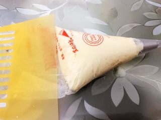 10、酥酥的香草曲奇小花,裱花袋里装入曲奇花嘴，装入面糊用刮板推刮到最底部后，剪开裱花袋