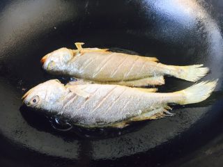 9、#感恩节食谱# 香煎小黄鱼,大火起锅，锅热放入约2勺左右的油，当油六成热时放入鱼，此时改中小火。 煎鱼时随时微微调整火的大小，千万不要让油起烟。 六成热的油温是如何判断呢，就是油面有明显的波动。 往油锅里放鱼时，用双手分别拎住鱼头和鱼尾，贴着油面轻轻地放入。 我使用的是不粘锅。 如果小伙伴们使用的是铁锅就要把锅烧的热热的，然后用姜在锅里涂抹一层，再继续操作。