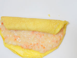 11、胡萝卜虾泥蛋卷,将蛋皮摊开均匀的抹上一层虾泥，靠近身体的地方留出一点不要抹，因为卷起来的时候虾泥会自动带蛋皮边缘来