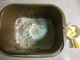 1、红豆沙餐包,将黄油以外所有的原料放入面包桶，先放水，糖和盐对角的位置放入，再放入高粉、低粉和奶粉，铺满水面，然后在面粉顶部掏一个洞，把酵母倒进去。