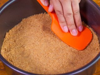 5、【免烤箱蛋糕】零失败芒果慕斯蛋糕,将处理好的消化饼干铺在蛋糕模的底部，压实后送入冰箱冷藏备用。