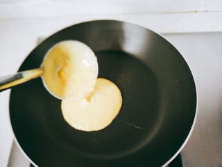 14、【宝宝辅食】无油香蕉牛奶鸡蛋松饼,开小火，不要油。勺子在锅的正中间倾斜，让蛋液顺滑的流下去，不要动。那样出来的面饼会是一个圆形，或者是接近圆形。放在正中间是为了受热更均匀，建议一次煎一个。如果锅里同时铺满了几个的话，那有可能正中间的都黑了，边上的还没有成型。