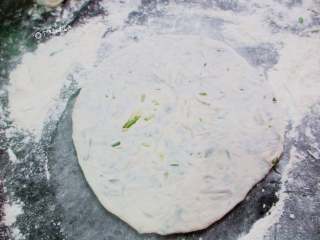 9、韭菜粉条薄饼,包好的面团用擀面杖慢慢向周围擀平，馅料露出来也没关系，擀成薄饼，一面撒上炒熟的白芝麻稍稍按压一下。