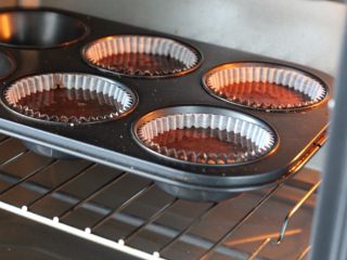 7、万圣节蜘蛛杯子蛋糕,将纸杯放入六连模具中，倒入面糊至纸杯的八分满，一共可以做四个纸杯蛋糕，要想多做一些就把食材翻倍。然后放进烤箱中层，上下火170度烤25分钟左右，取出移至烤网晾凉备用