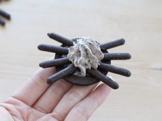 12、万圣节蜘蛛杯子蛋糕,取一片奥利奥饼干挤适量淡奶油，再分别插上百奇巧克力棒当作蜘蛛腿