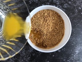1、芒果慕斯蛋糕,将融化好的黄油倒入饼干末中,搅拌均匀