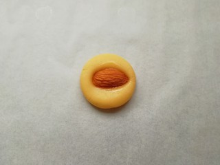 11、黄油杏仁饼干,取一个搓好的小圆球压扁，再取一粒大杏仁，在装蛋液的小碗里沾上一点蛋液，放在压扁的面团中间，稍微用力压一下，一个杏仁饼干就做好了。