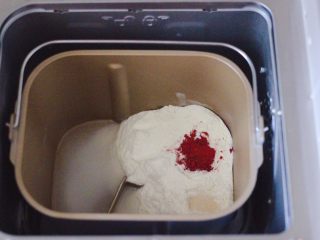 1、粉嫩蔓越莓果仁芝麻饼,首先把称重的中筋面粉和清水，酵母和红曲粉放入面包桶里，启动面包机的和面程序开始和面。