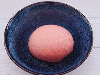 2、粉嫩蔓越莓果仁芝麻饼,和好的面团揉圆后，放入容器里，盖上保鲜膜进行一发。