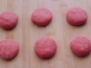 12、粉嫩蔓越莓果仁芝麻饼,依次包好所有的饼胚后，用手摁扁。