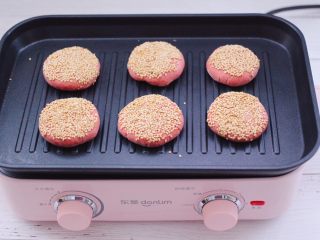 15、粉嫩蔓越莓果仁芝麻饼,把做好的饼胚，放入平底煎锅里。