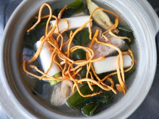 8、虫草花海带脊骨汤,加入海带结，葱姜，虫草花和足量的水（如果煮的过程中水实在太少可适量加入温水或热水），先大火煮开再转中小火加盖煮1-1个半小时。（在熬制骨头汤时，中途不要往锅中加冷水，否则，汤温骤然下降，会使骨中的蛋白质等迅速凝固而变性，收缩成团而不再解聚，肉质表面的空隙也会因此而收缩，造成肉骨组织紧密不易焖酥，骨髓内的蛋白质、脂肪无法大量溶出，这样不仅影响汤中的营养含量，而且也影响汤味的鲜香程度）