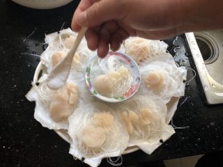 5、粉丝蒸扇贝,每个贝壳上撒一点细盐和料酒。