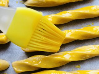 10、苹果磨牙棒,打开一个蛋黄。每一条磨牙棒均匀的刷上蛋液,这时候烤箱180度预热