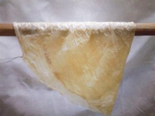 14、纯手工豆腐皮,再将豆腐皮对折,架在锅上方的竹架上,进行初步控干水分。