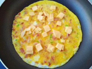 10、芝士火腿鸡蛋卷,蛋液稍稍凝固，均匀的撒上芝士片