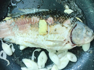 6、奶白鲫鱼豆腐汤,切好的大葱放入锅中一起煎，鲫鱼煎黄后翻面继续煎。