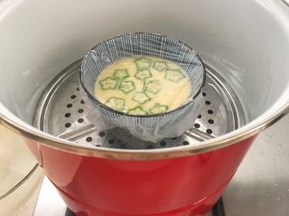 7、宝宝辅食12M➕ 秋葵牛奶蒸蛋羹,蛋液上放上一些秋葵薄片，盖上保鲜膜，保鲜膜上牙签扎几个小孔，水开后再放上锅，中小火蒸10分钟即可