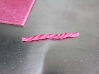 9、火龙果磨牙棒（适合9个月以上的宝宝）,拿一根长条面团，左右按住一头，右手按住另一头，分别往两个方向搓成麻花劲即可