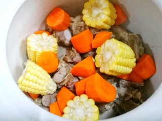 4、胡萝卜玉米排骨汤,锅中放入排骨、玉米、胡萝卜。