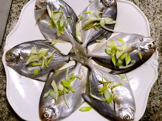 3、清蒸鲳鱼,淋上料酒和盐再撒上葱和姜丝腌制半小时