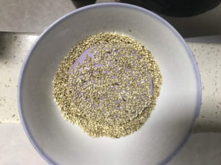 16、紫薯芝麻饼,碗里倒入熟白芝麻,把饼坯两面都粘上一层白芝麻