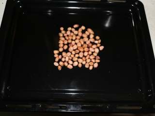 1、美味花生酥,生花生放在烤盘上。