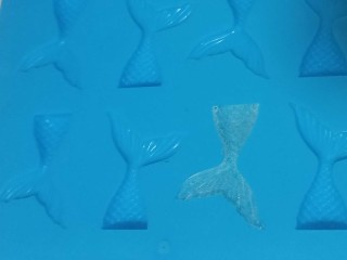 12、艾素糖造型水果蛋糕,把糖浆倒入美人鱼尾硅胶模具中，边角可以用牙签调整一下。