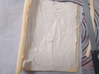 9、不易开裂的轻盈蛋糕卷,把淡奶油，马斯卡彭芝士，砂糖混合一起打发，摊开固定好的蛋糕片，一边会有微卷的定型，微卷这边奶油要抹的厚一些，另一边则抹的薄一些，最边缘用蛋糕刀割开一个斜边。