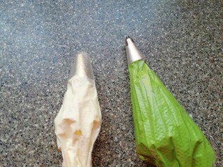 24、圣诞奶油蛋糕,剩下的淡奶油继续打发至9分发，取一个裱花袋装入小号圆孔裱花嘴，装入一小部分白色的奶油备用，将剩下的奶油加入绿色的色素，调出圣诞树的颜色，另外取一个裱花袋装入小号八齿裱花嘴，装入绿色的奶油备用。