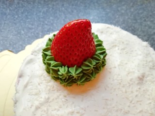 25、圣诞奶油蛋糕,两颗草莓洗干净擦干水分，选一个“瘦高型”的草莓，削平底部，固定在蛋糕的一边，用绿色的奶油裱出圣诞树，如图。